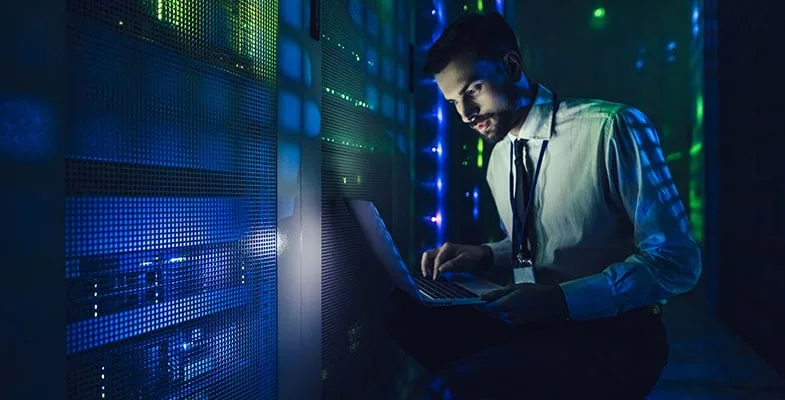 Man is working in data centre with laptop.