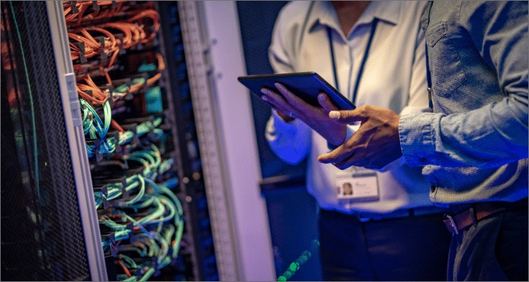 man in server room looking at a tablet