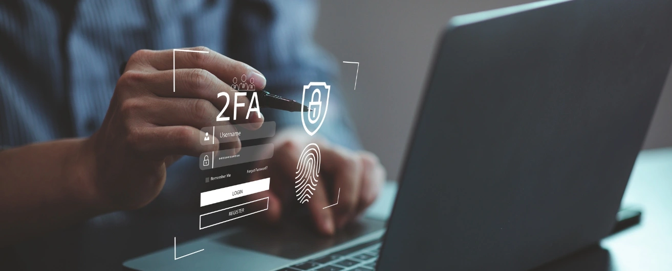 A person interacting with a holographic interface displaying two-factor authentication (2FA) elements. The interface shows icons for username, password, a shield with a lock symbol, and a fingerprint, while the person types or points with a pen near a laptop.