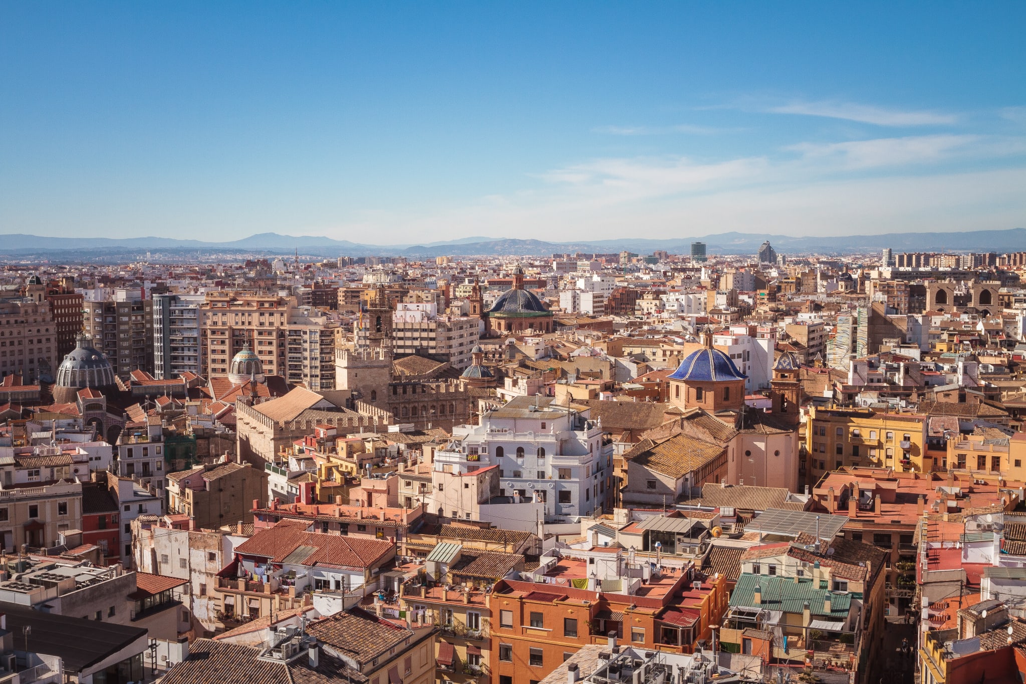 Aerial view of a city that is off the beaten path, showcasing a blend of historic and modern architecture. Nestled against majestic mountains under a clear blue sky, this locale offers vibrant LGBTQ+ experiences. This hidden gem stands out among off the beaten path gay cities, providing an inclusive atmosphere amid stunning natural scenery.