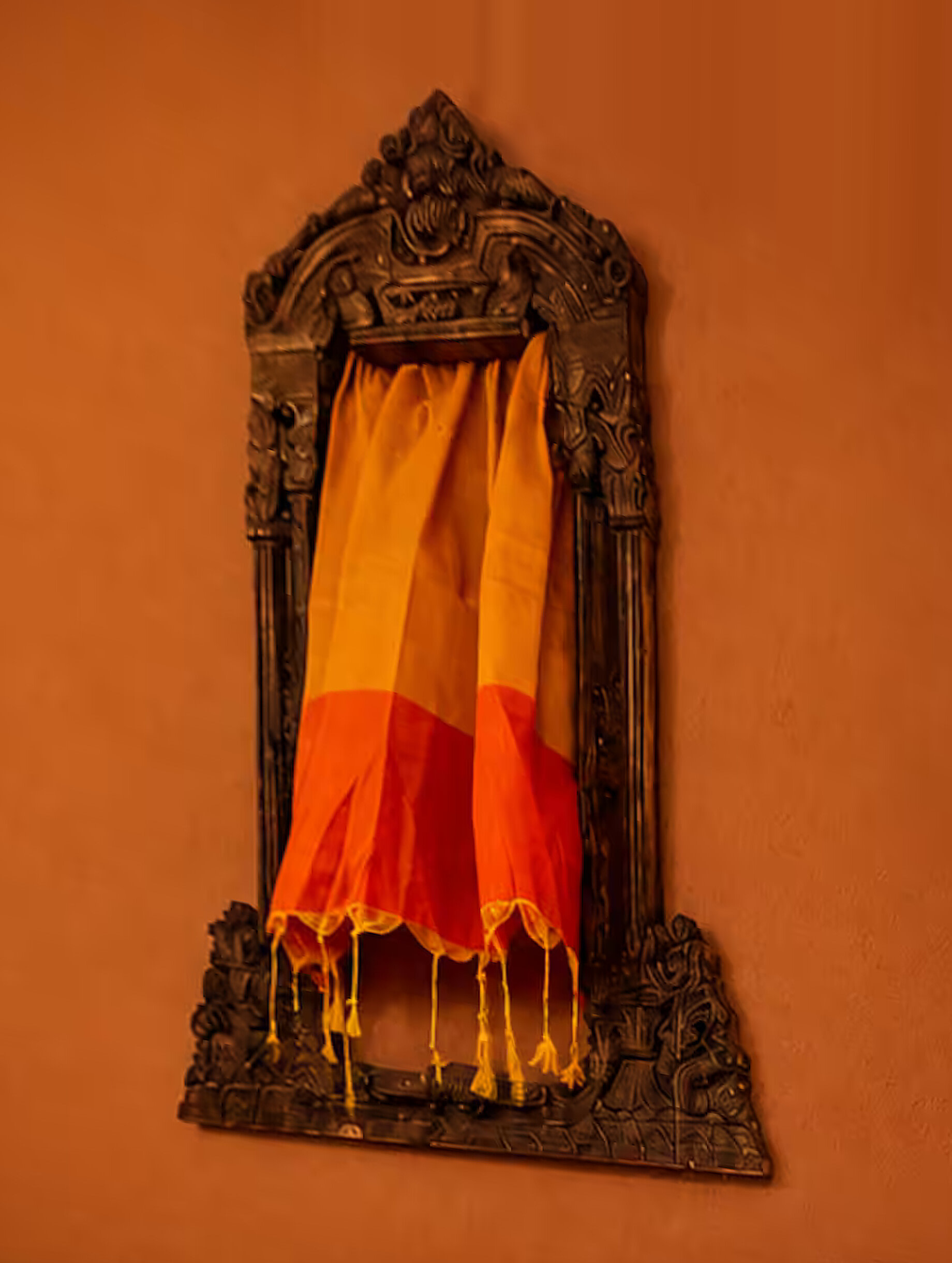 The carved wooden darwaza on the terracotta wall of the Darwaza Room at Moksha Stays Kashi