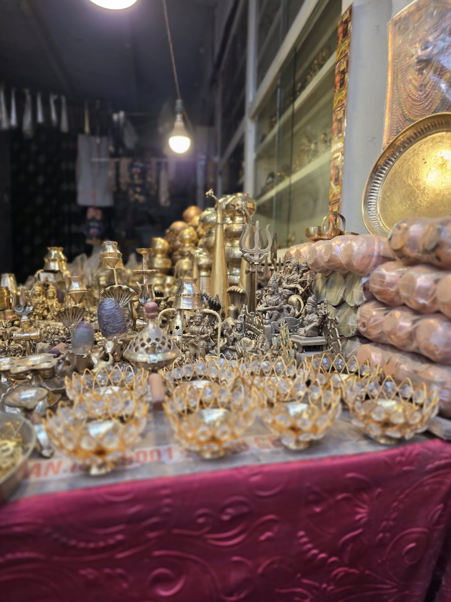 Brass lamps, diya holders and figurines of deities displayed at a market stall in Varanasi