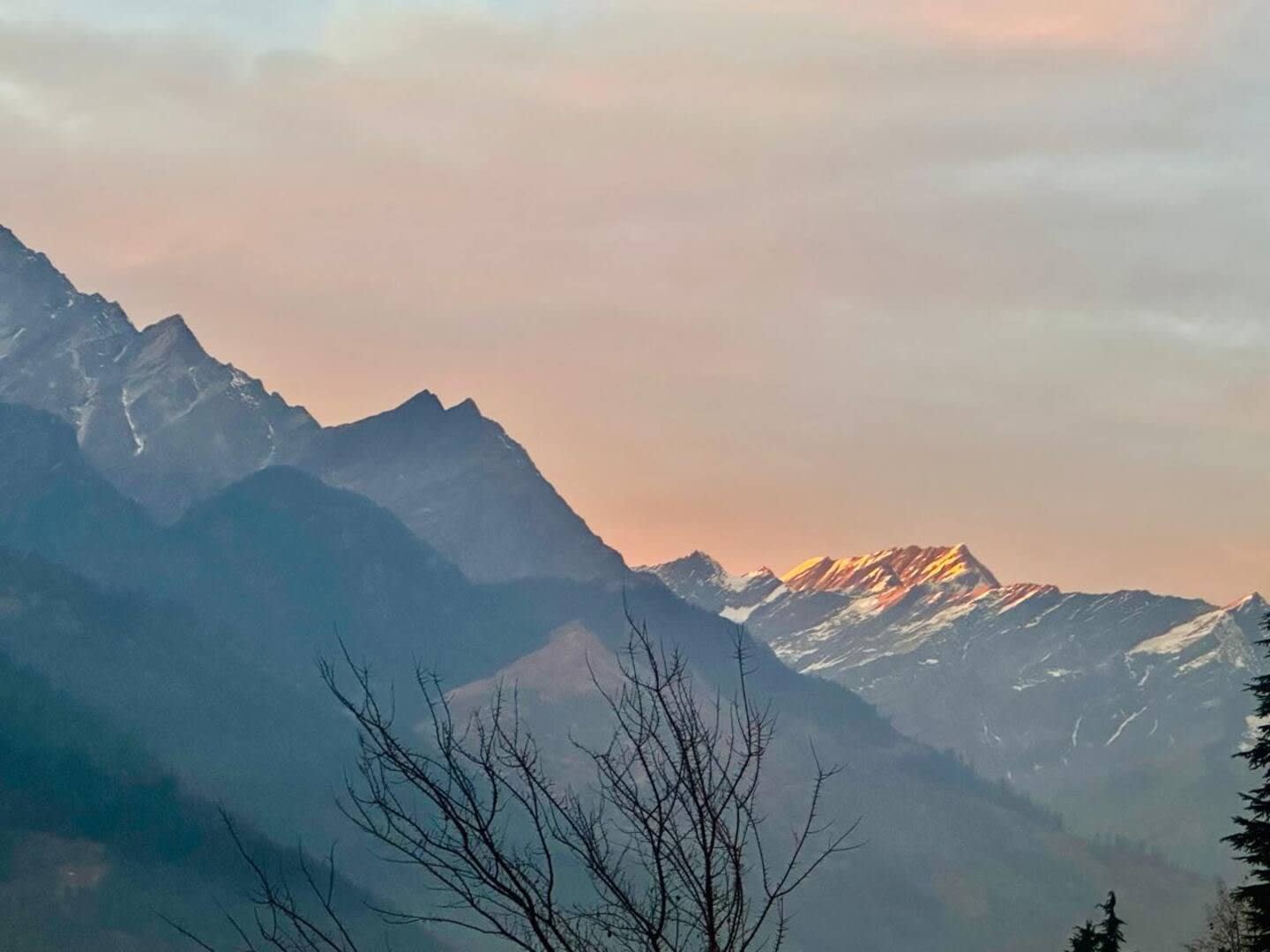 Mountain ridges glowing pink at sunset under a soft sky