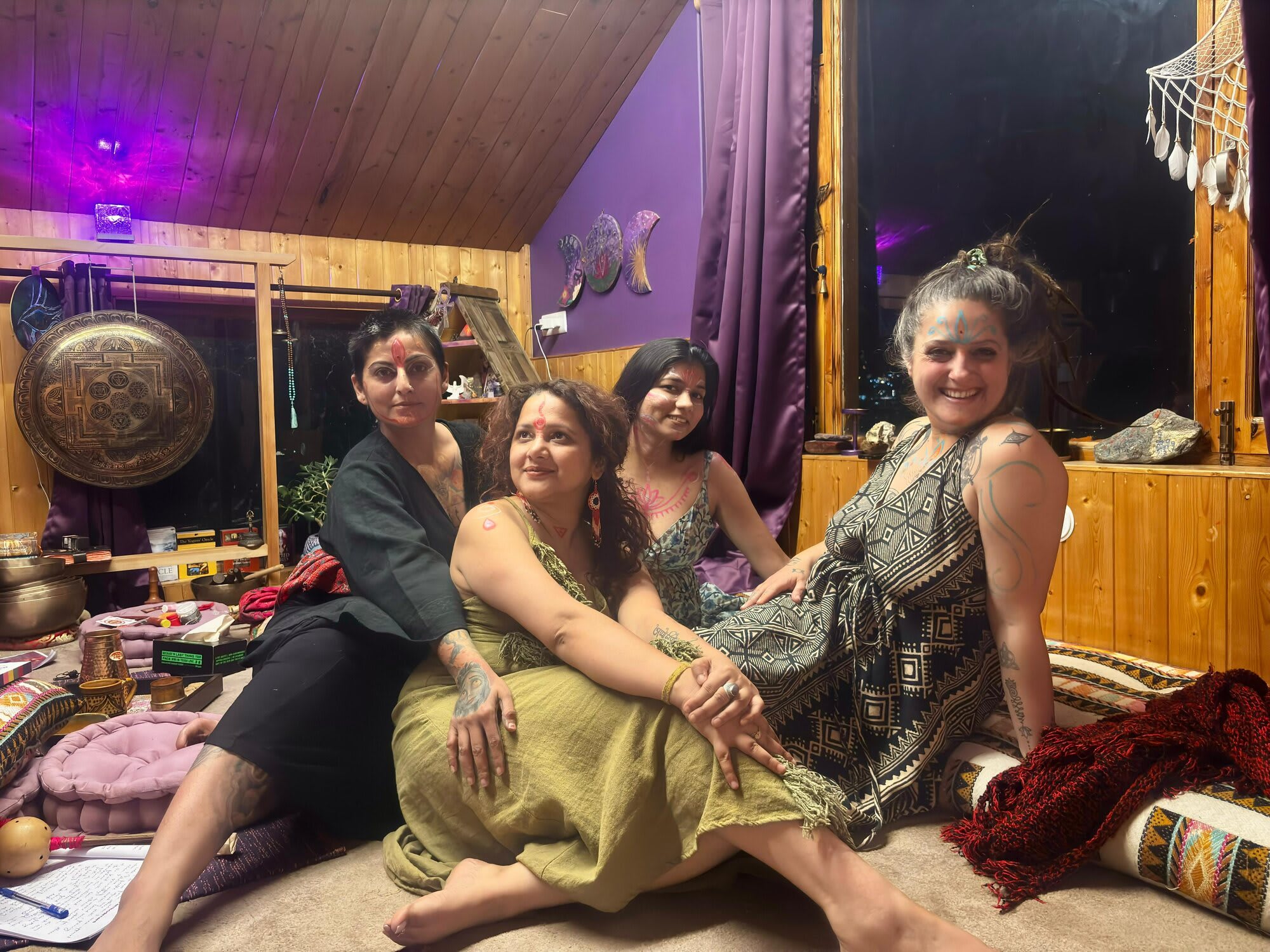 Four women in a sound-healing room at Sehar, sitting together among singing bowls, a gong and floor cushions