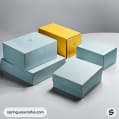 Stack of pastel blue and yellow gift boxes on a gray surface.