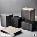 Assorted sleek cardboard boxes in black and beige tones, various sizes, on a reflective surface.