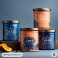 Four decorative jars with floral designs in blue and peach hues, placed on a table beside a sliced orange and herbs.