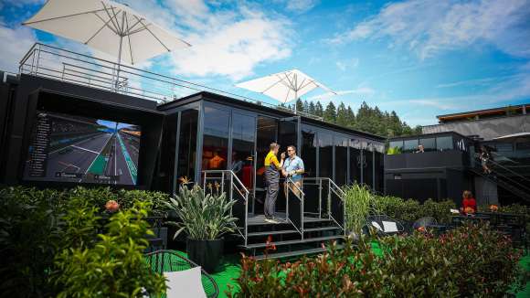 A hospitality set-up at a formula 1 race with two men standing in front of it.