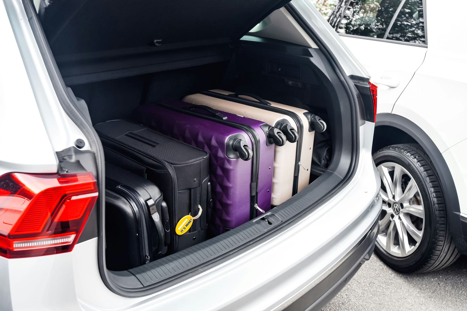 Three large suitcases packed into the trunk of a car, ready for a trip