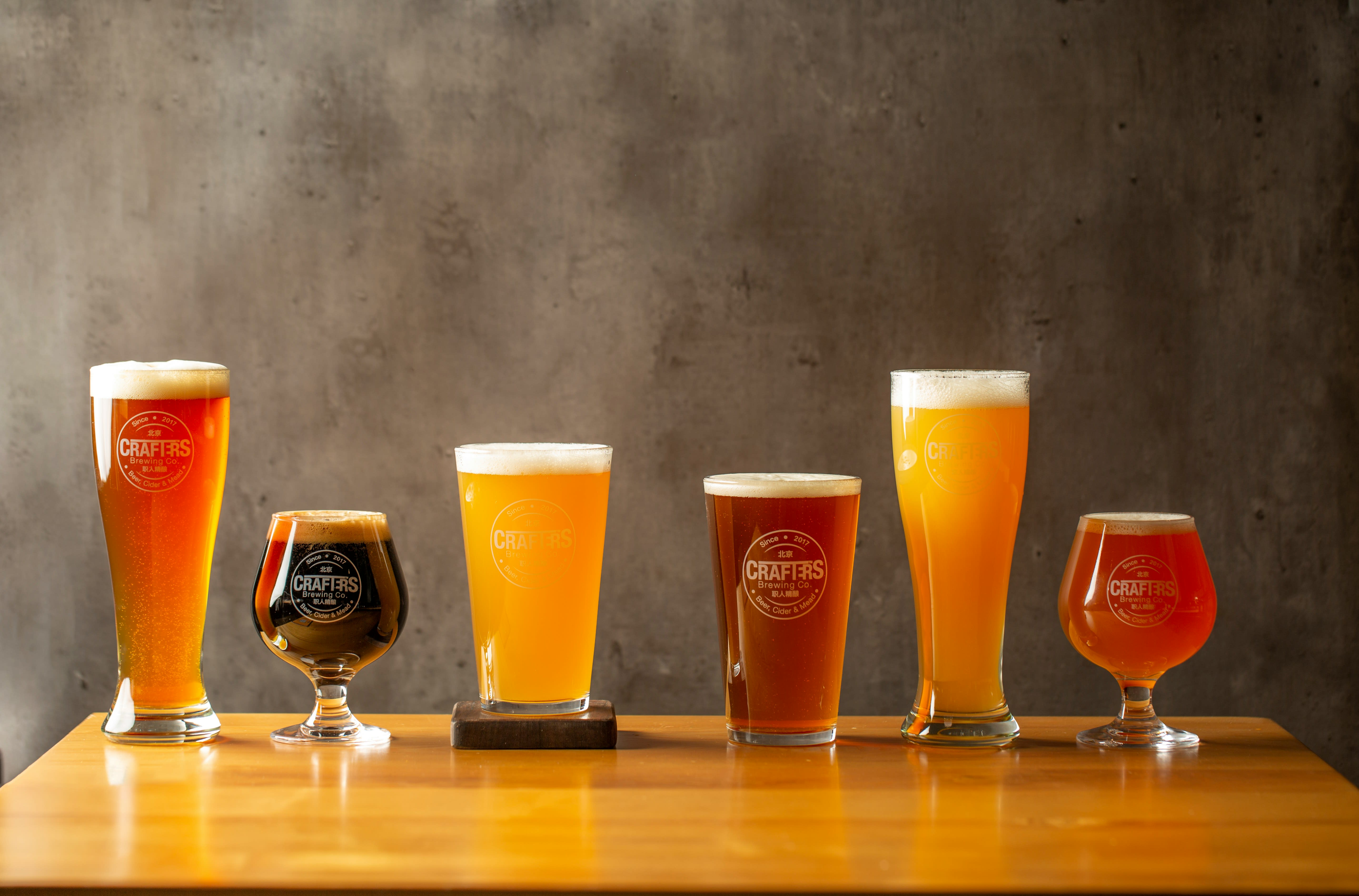 A row of beer glasses showcasing different styles, from light lager to dark stout