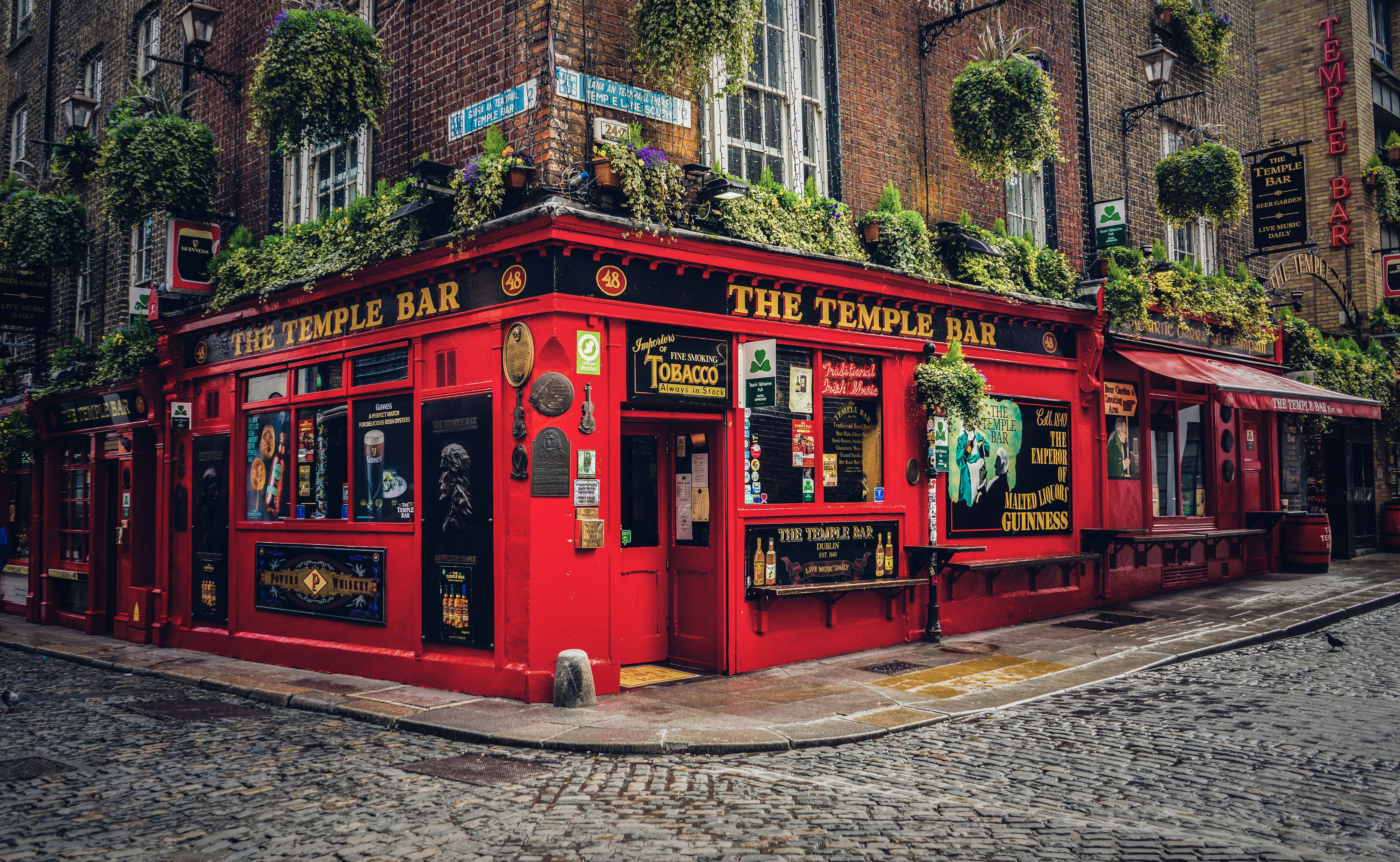 The red facade of The Temple Bar pub on a cobblestone street in Dublin