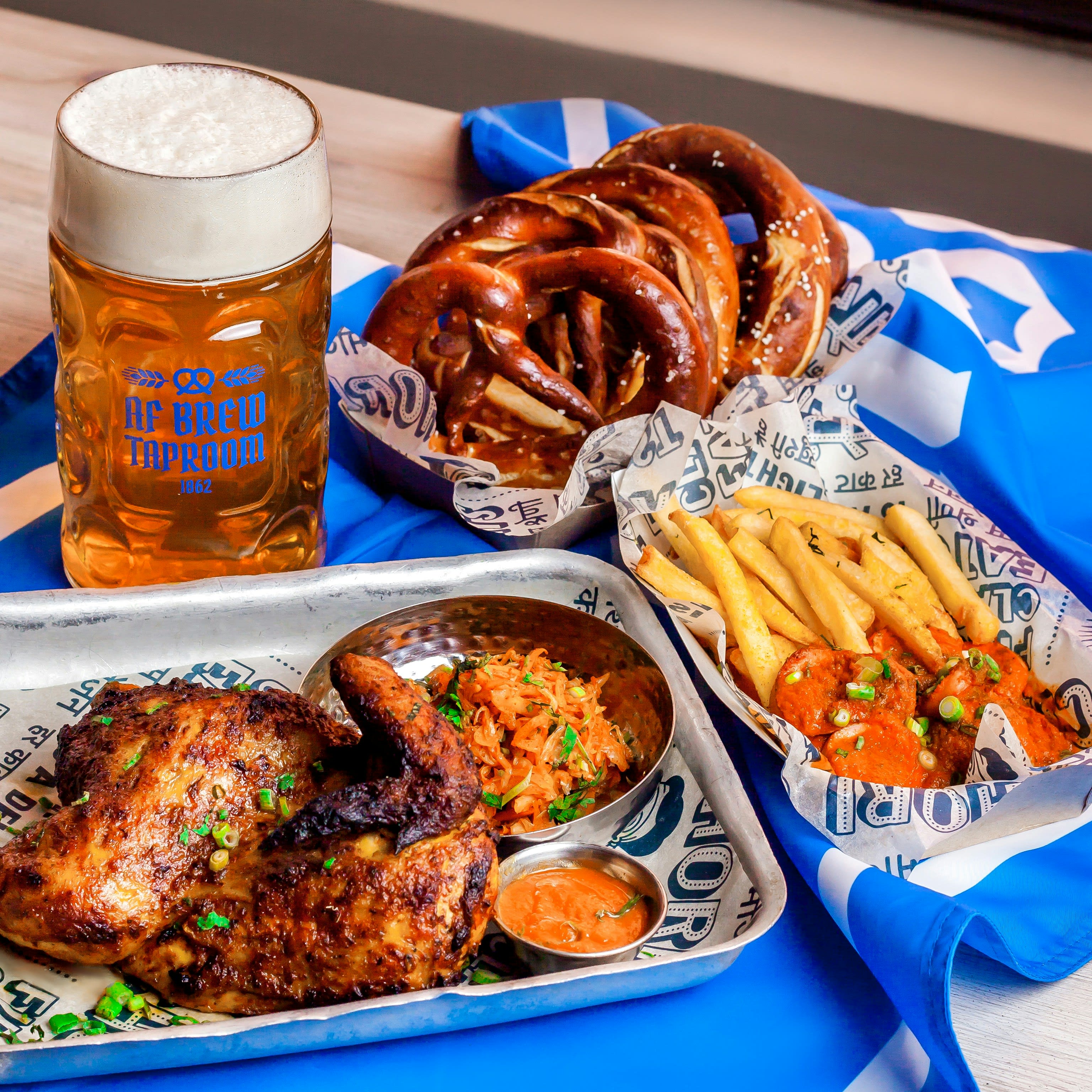 A Bavarian beer stein, soft pretzels, and a beer hall food spread on a table