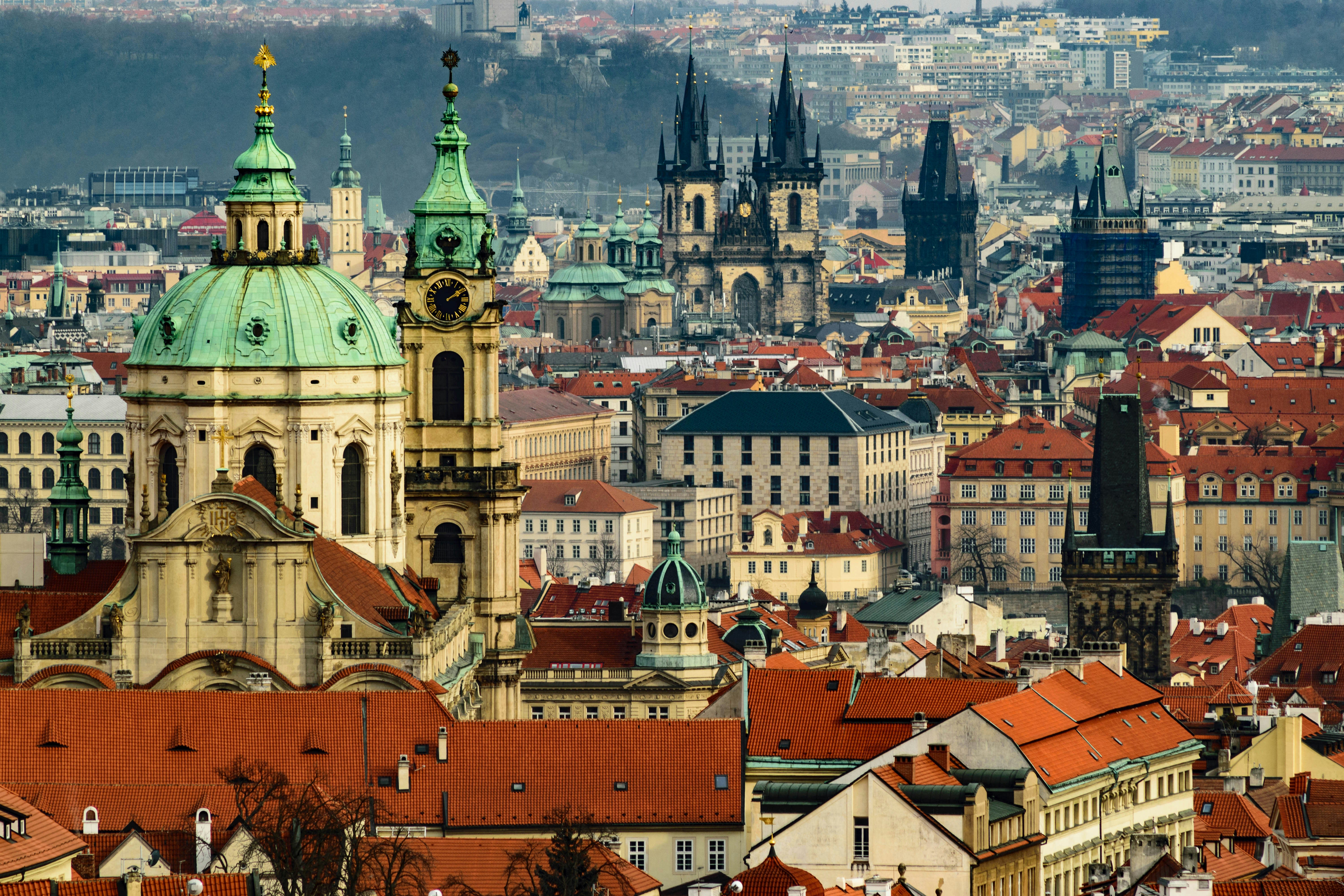 Prague's Old Town skyline, with the green dome of St. Nicholas Church and the spires of T&yacute;n Church rising above red-tiled roofs