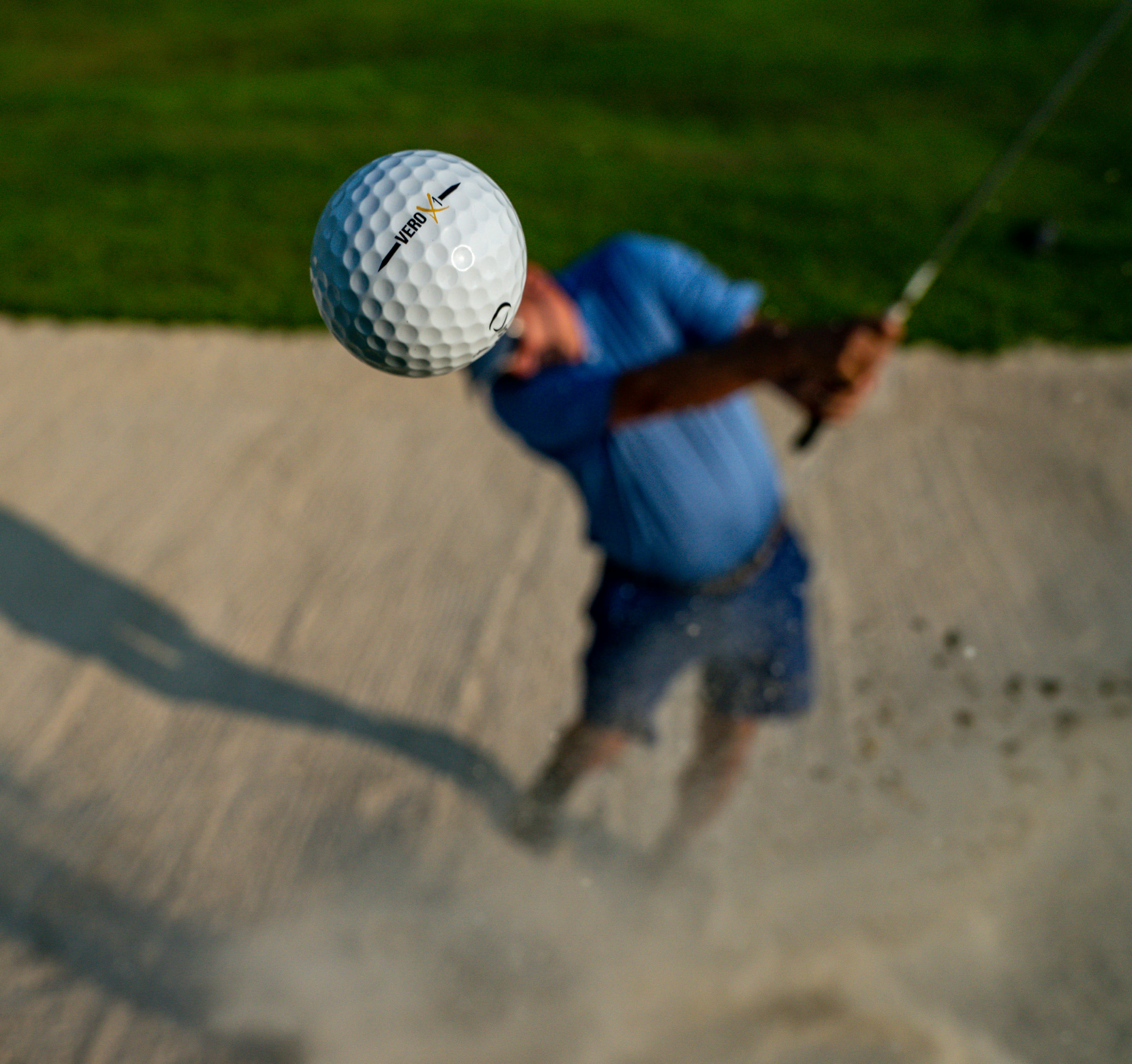 Golfer exploding out of a fairway bunker