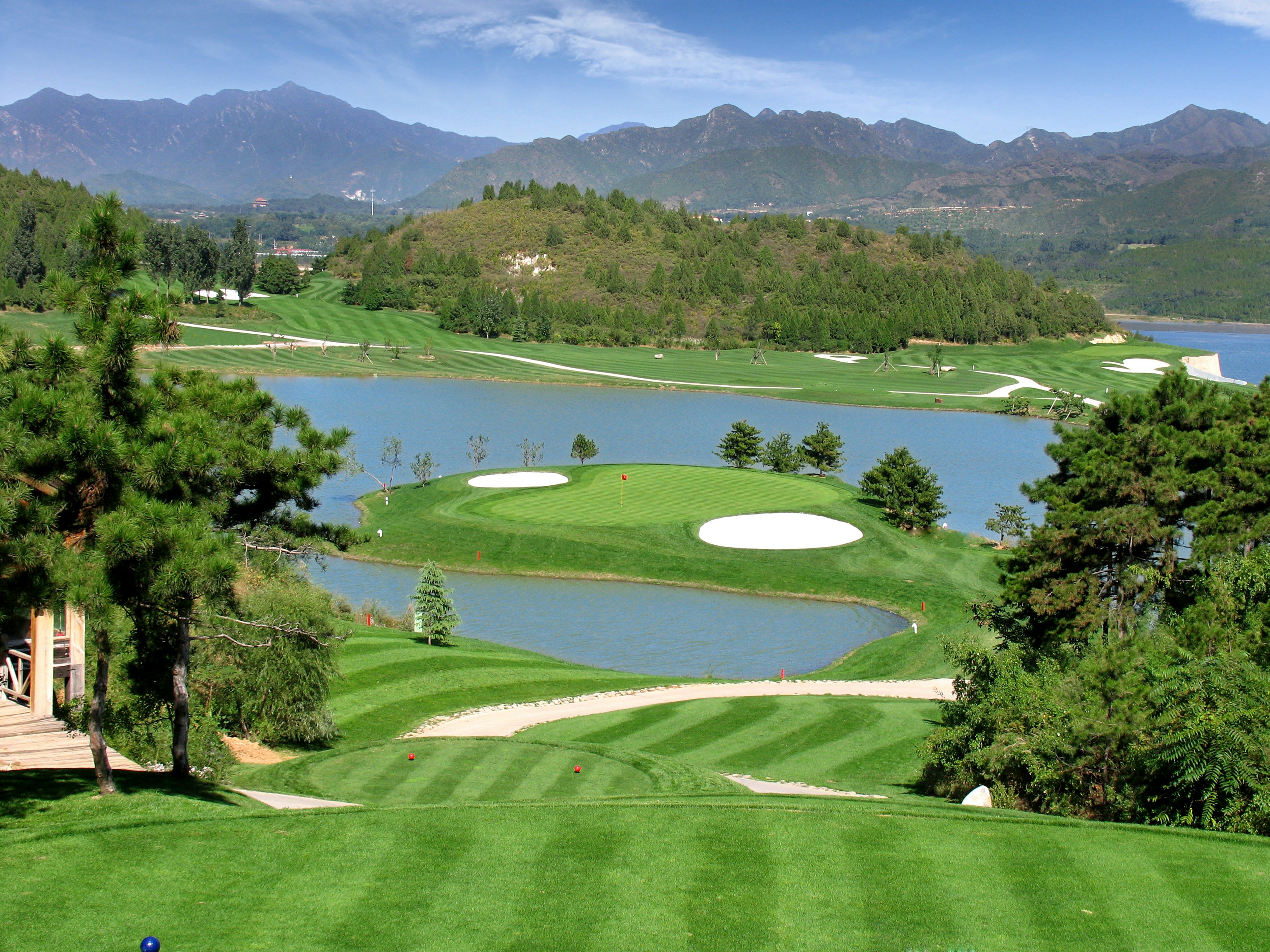 Lush golf course with water features and mountain backdrop in Southeast Asia