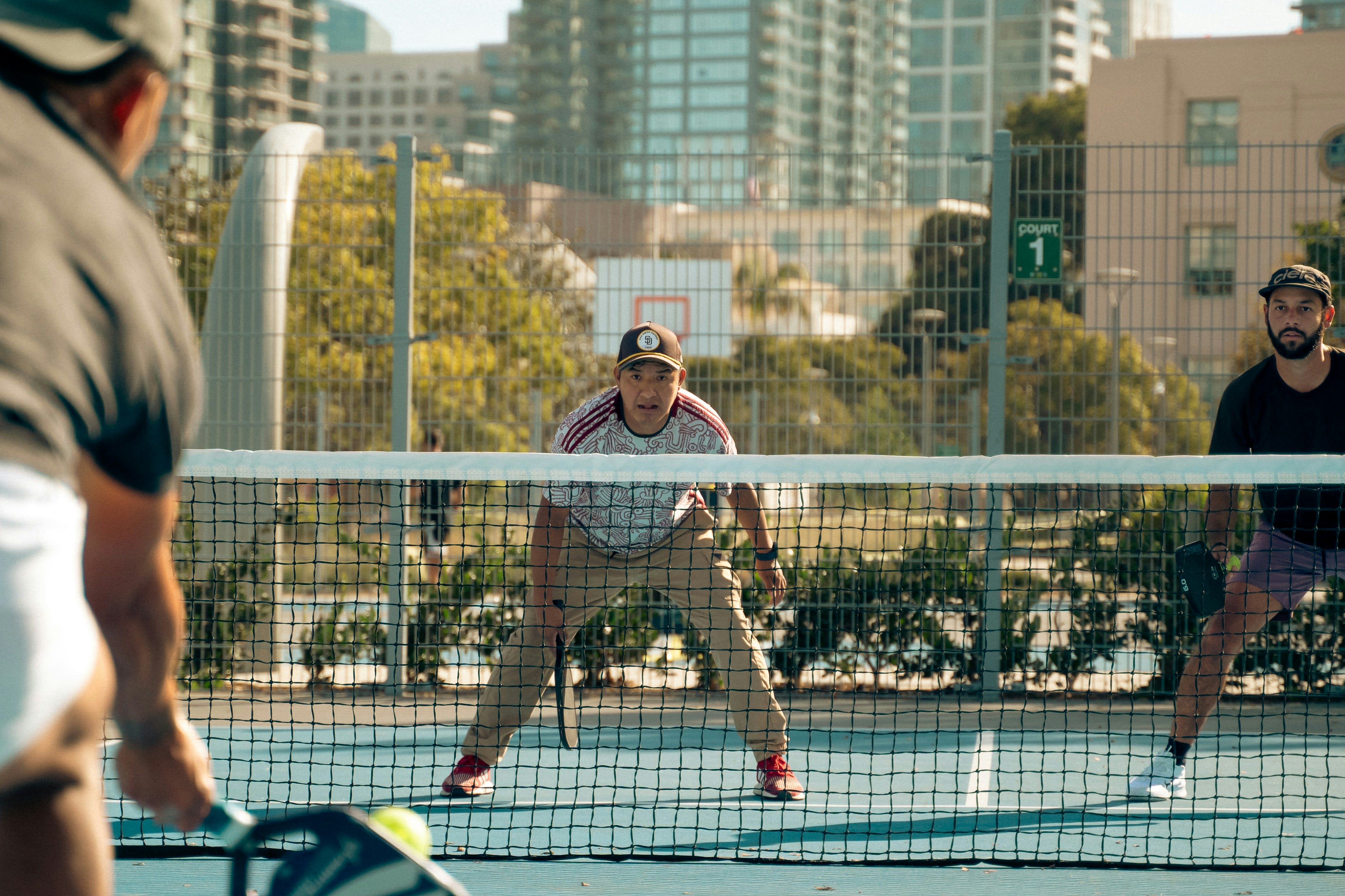 Two players facing off across the net at an urban outdoor pickleball court