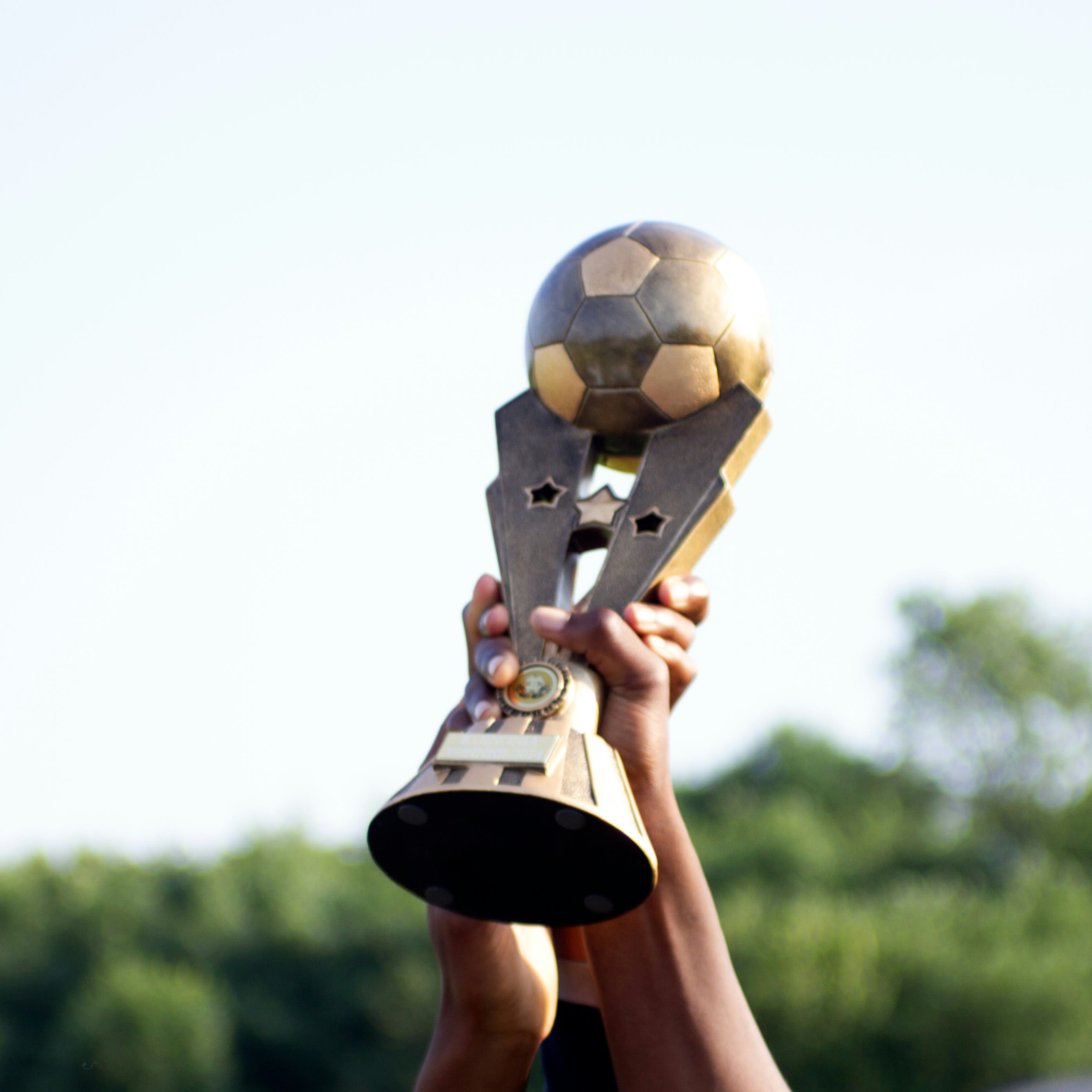 Young players lifting a soccer trophy together