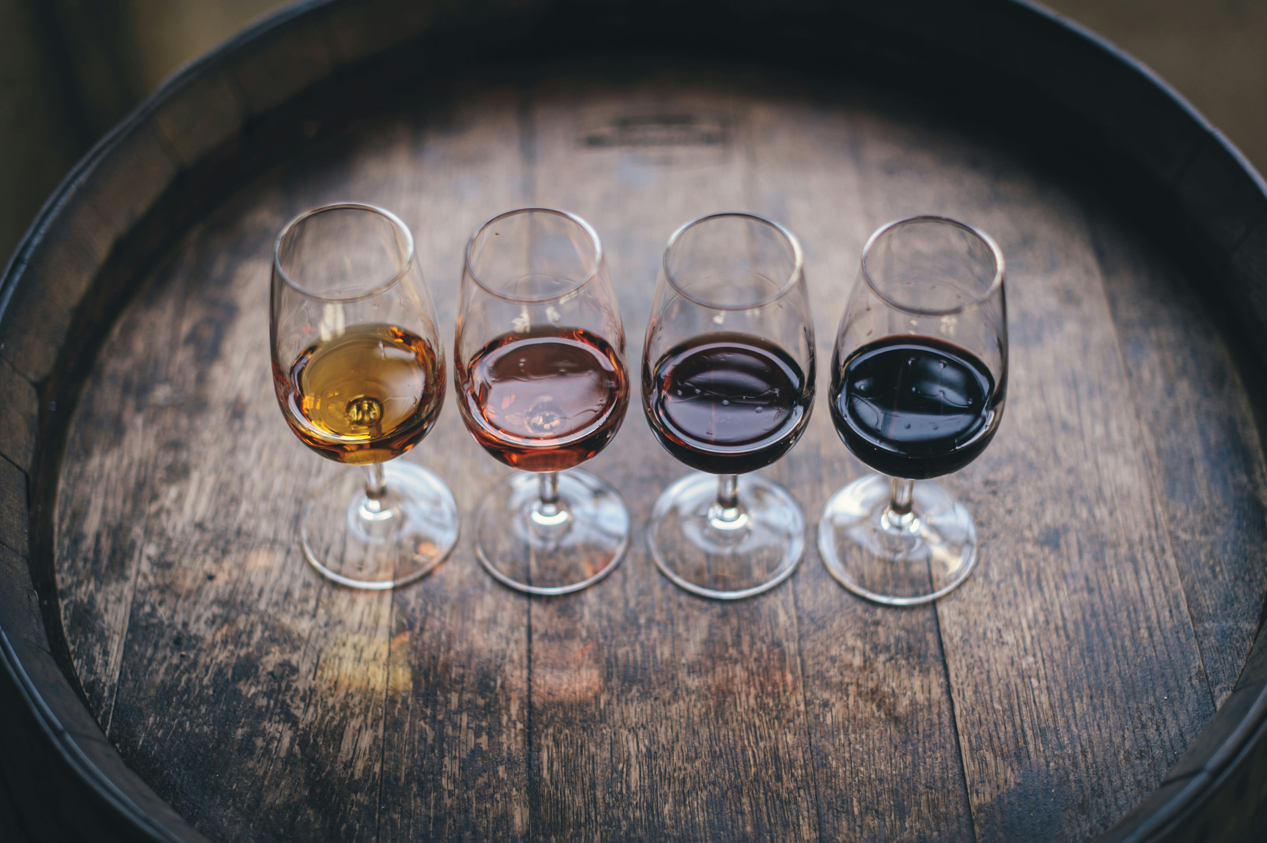 Four wine glasses in a flight arranged on an oak barrel