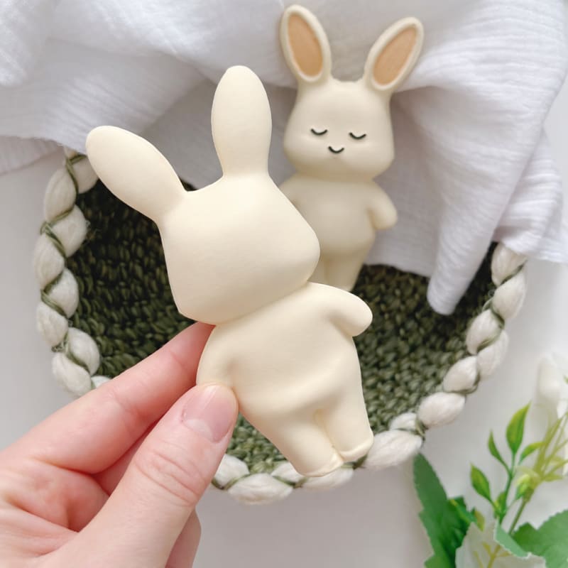 Hasır sepet ve müslin örtü üzerinde sergilenen tavşan diş kaşıyıcının pürüzsüz arka yüzeyi; ürünün dolgun yapısını gösteren detay çekim.