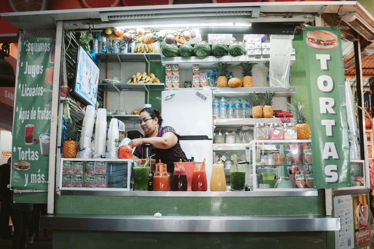 A vendor pours fresh juices at a market stall in Oaxaca de Juárez, Mexico