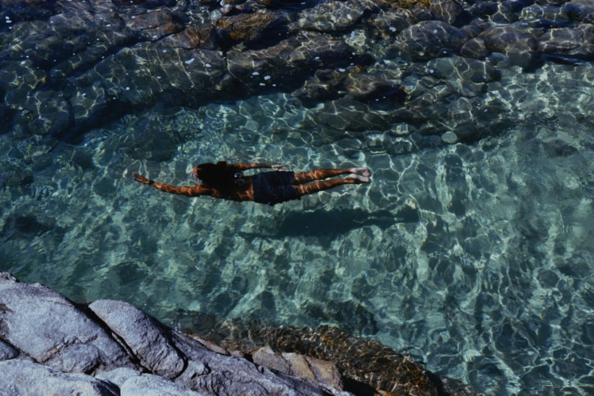 A swimmer in clear, calm water over rocks on the Mexican coast