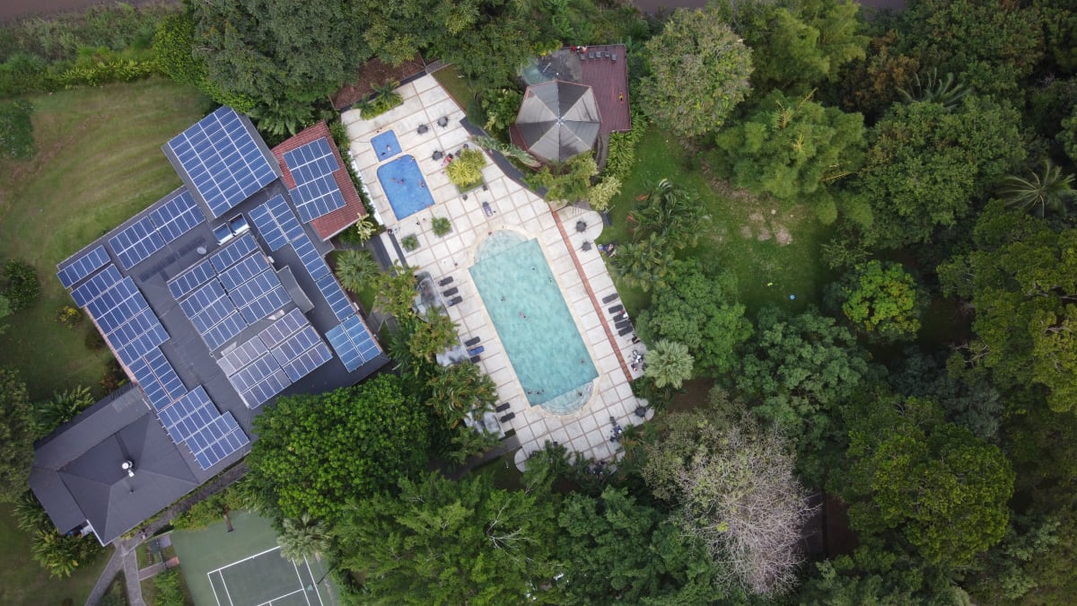 Vista aérea de villa de lujo ecológica con paneles solares y alberca privada rodeada de selva tropical — perfil de inversión en bienes raíces sustentables Puerto Escondido