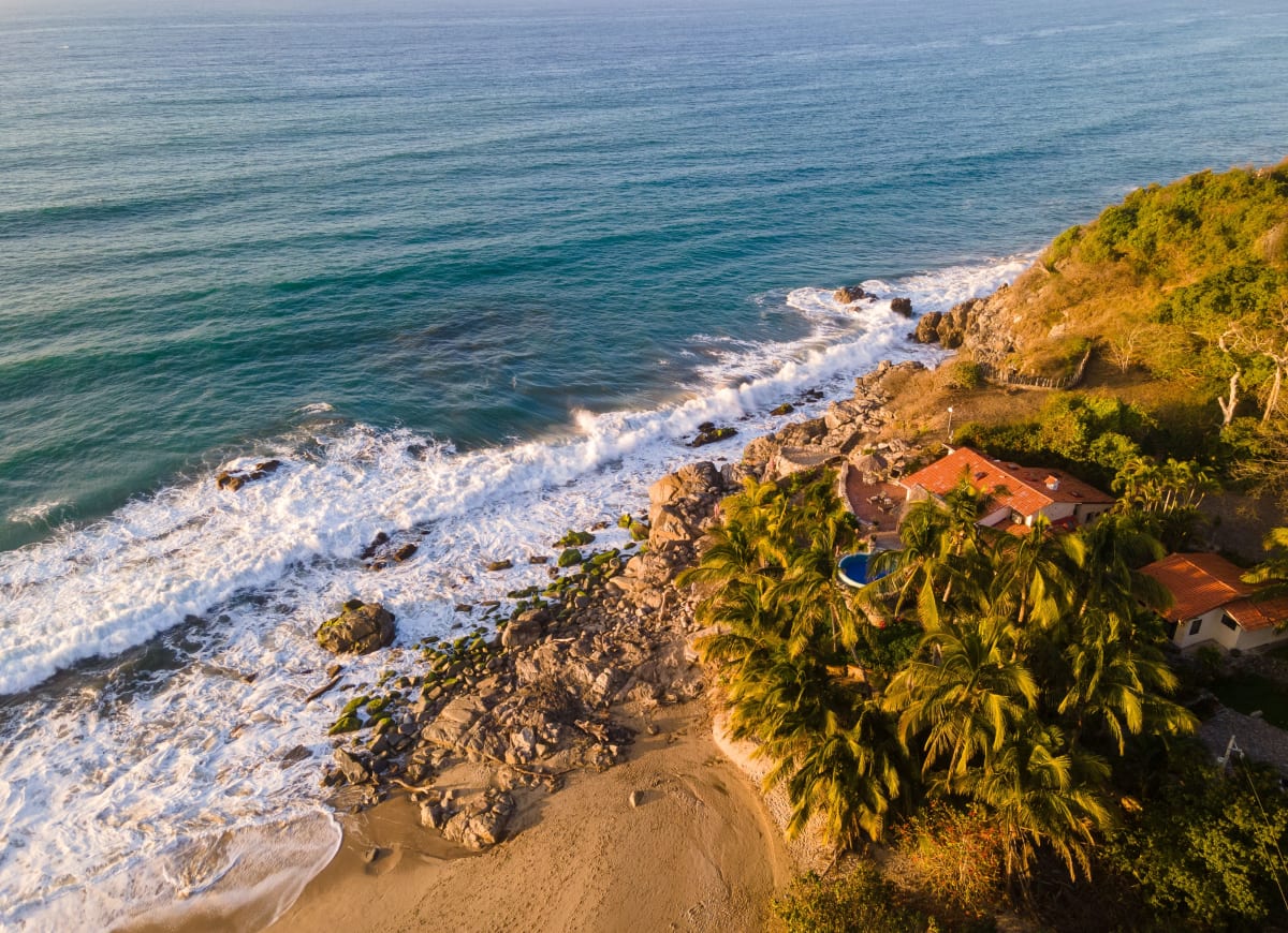 Vista aérea de casa frente al mar con palmeras en la costa del Pacífico mexicano — inversión inmobiliaria en Puerto Escondido