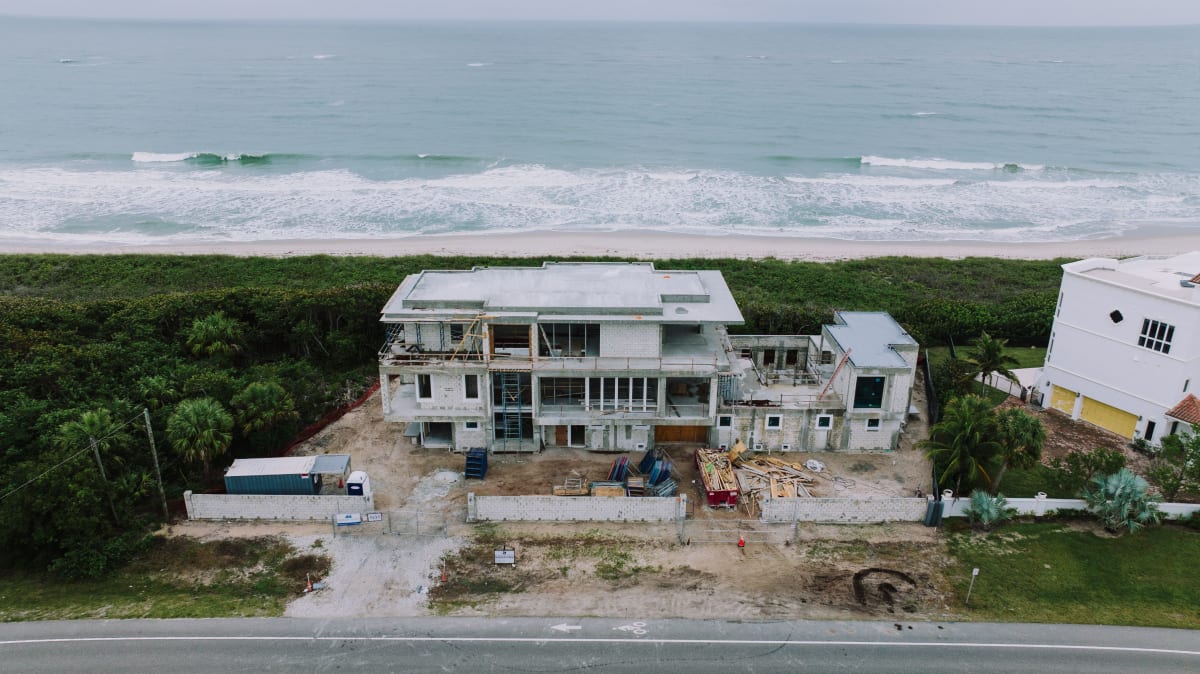 Vista aérea de casa en construcción cerca del océano rodeada de selva tropical — construcción de bienes raíces en Puerto Escondido 2026