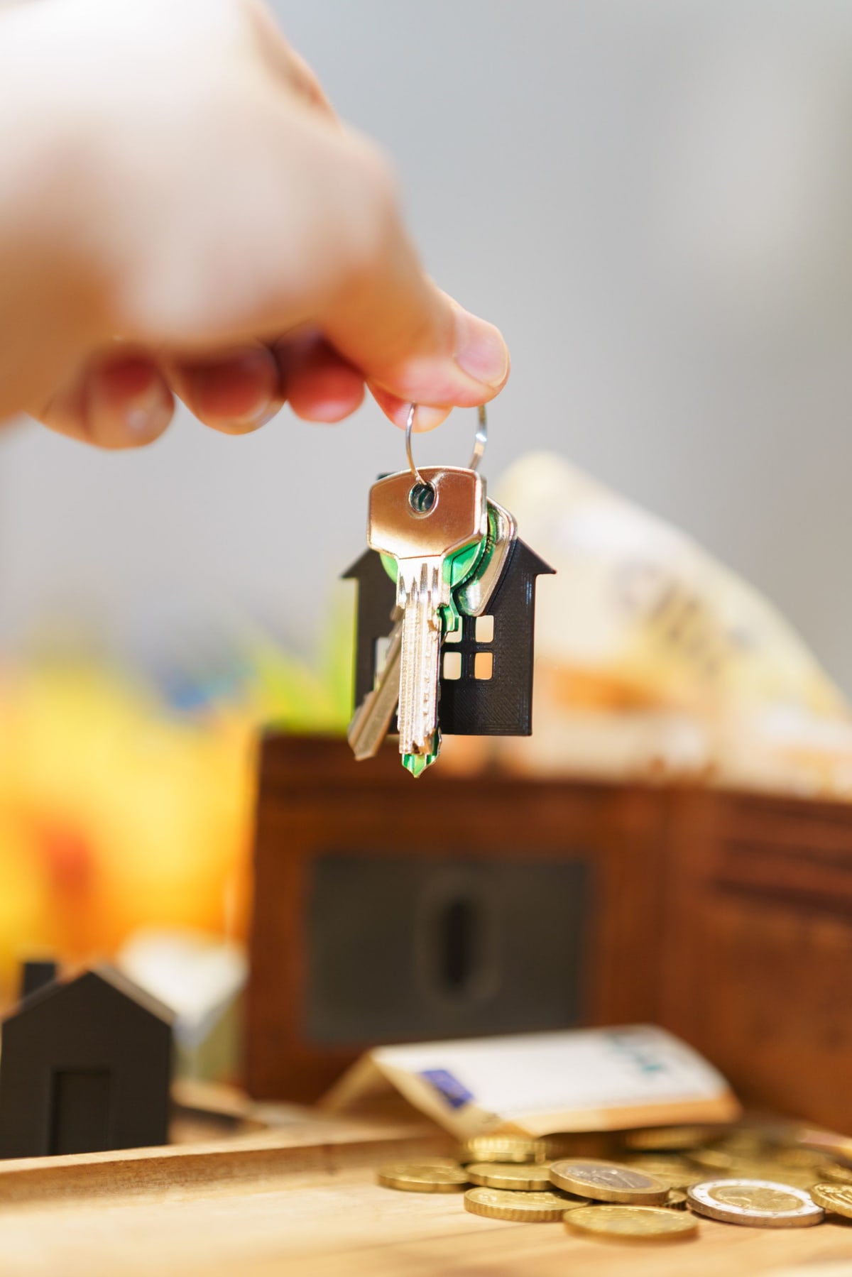 Hand holding house keys with coins, symbolizing the real estate investment value comparison between Puerto Escondido and Tulum