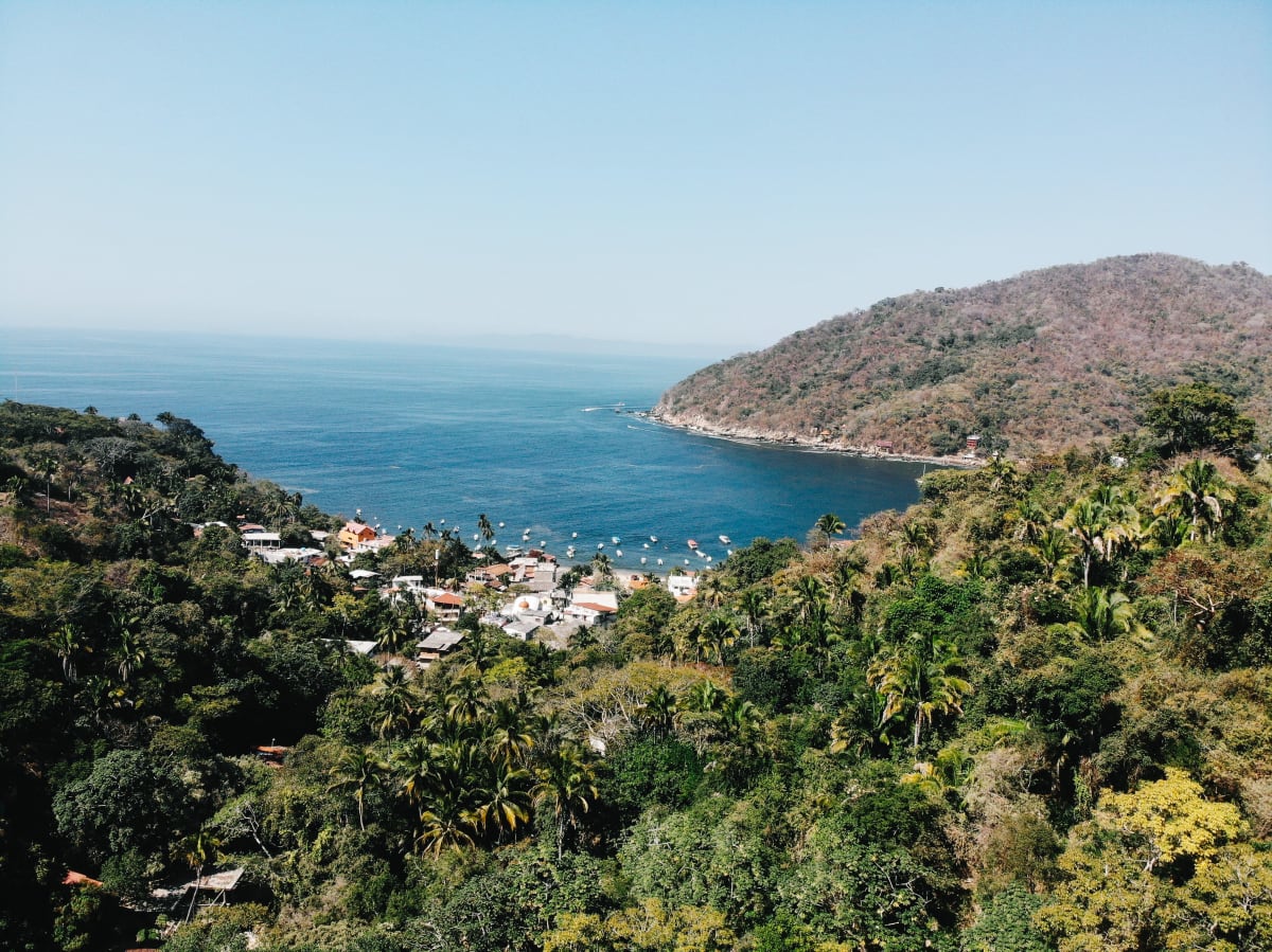 Pequeño pueblo costero en una bahía a lo largo de la costa de Oaxaca, México, representando los pueblos de etapa temprana cerca de Puerto Escondido y Huatulco con desarrollo inmobiliario limitado