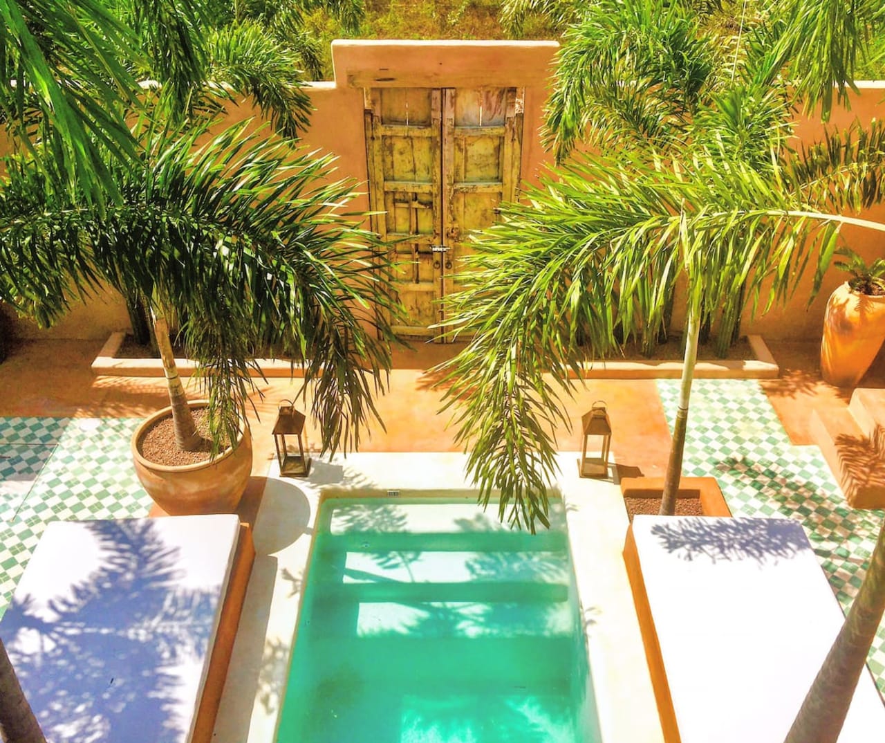 Área de alberca rodeada de exuberante vegetación tropical, con cómodos camastros para relajarse bajo el sol. El entorno combina detalles naturales y un diseño acogedor que invita al descanso y a disfrutar de un ambiente tranquilo y privado.