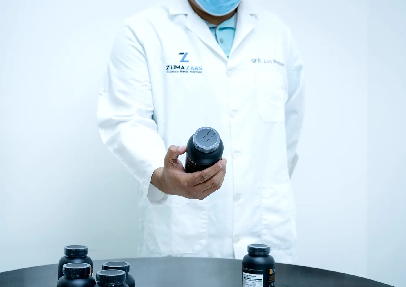 Integrante del equipo de Zuma Labs sosteniendo un bote terminado, con producto envasado sobre la mesa