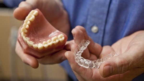 dentist holding a model of teeth and clear aligners