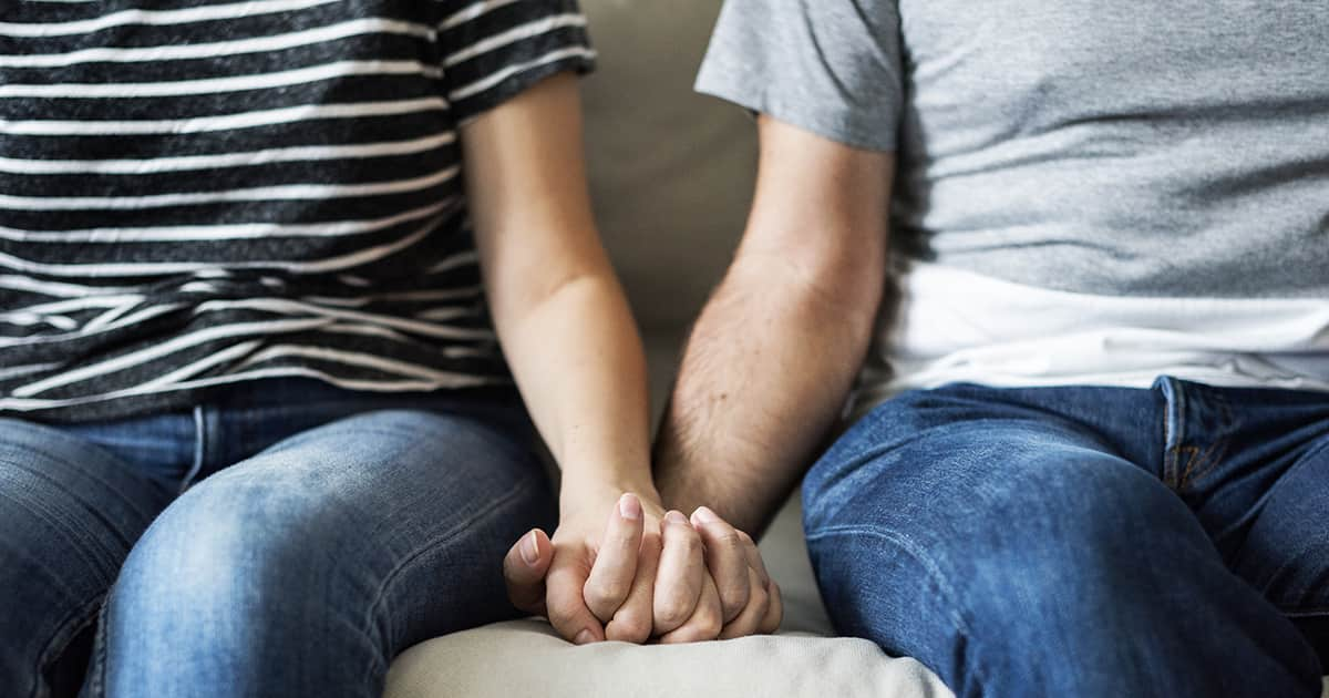 couple holding hands on a couch