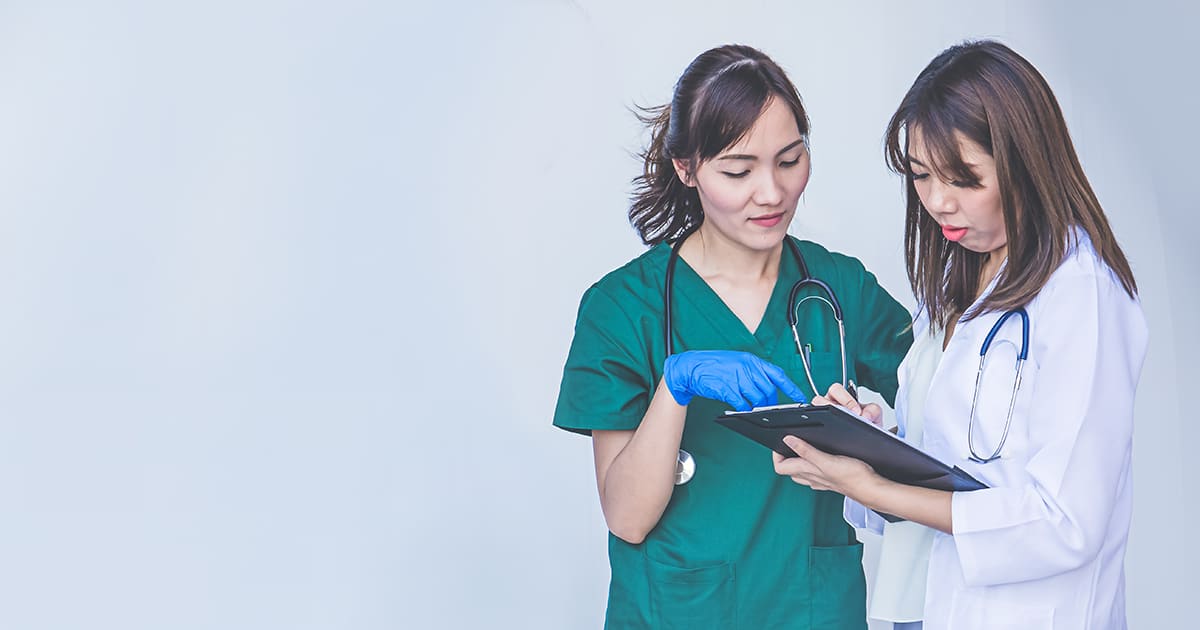 two medical staff talking to each other with a clipboard