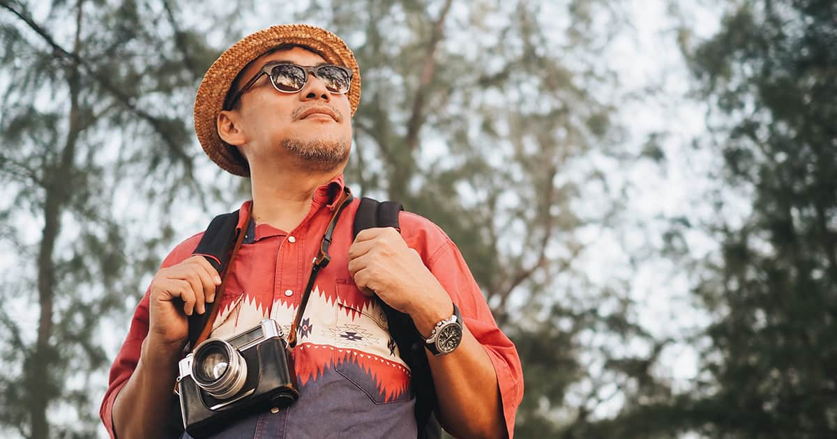 a man hiking with backpack and glasses and camera