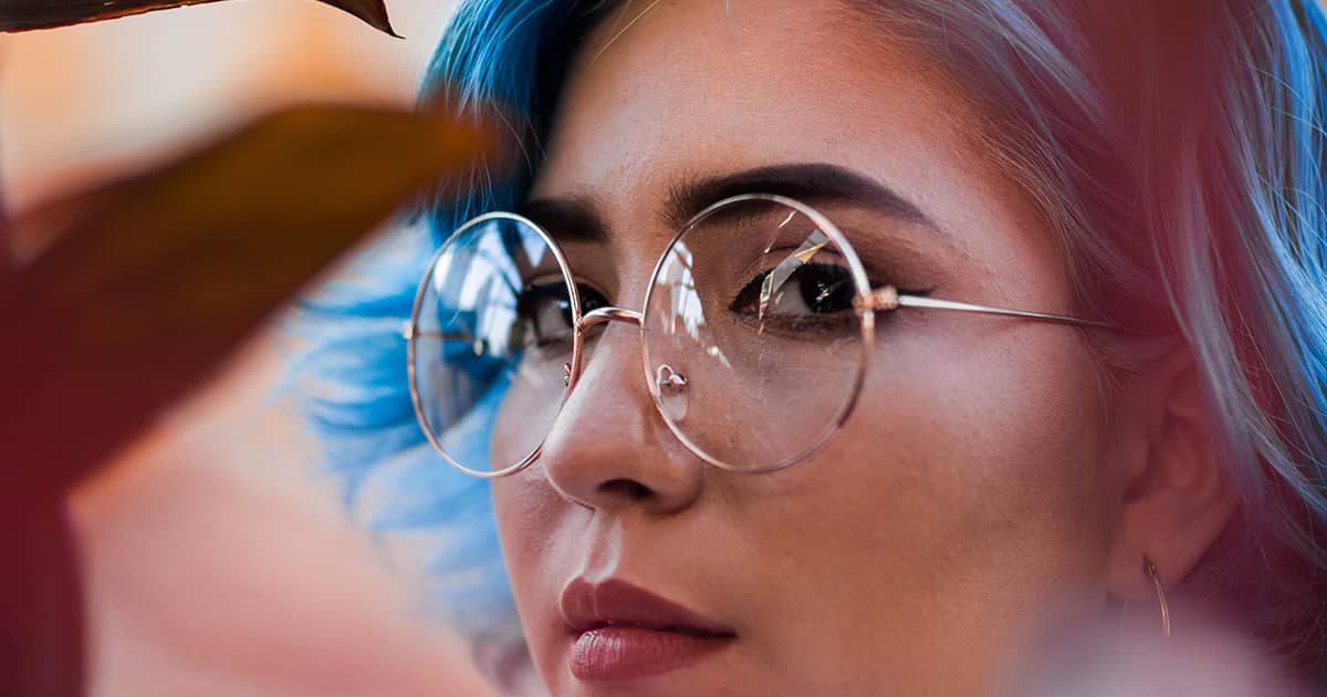 a woman with blue hair and glasses