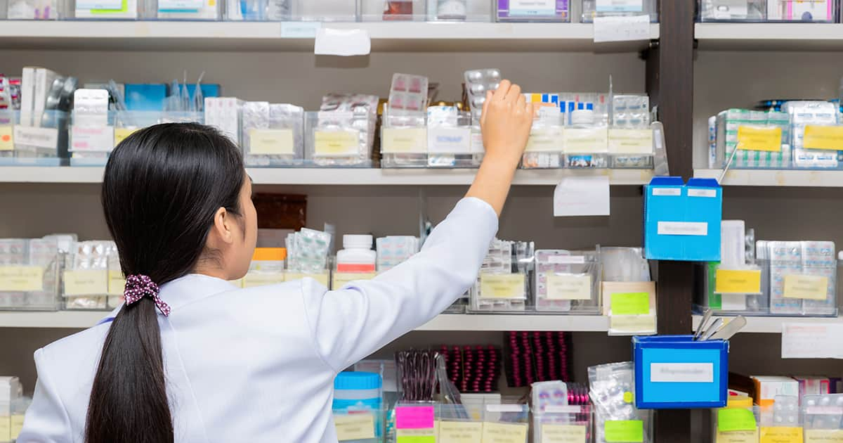 a pharmacist taking medication from a shelf