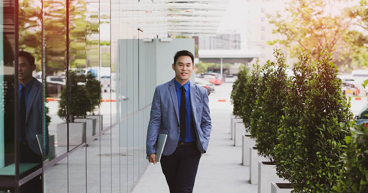 asian businessman walking in city with laptop