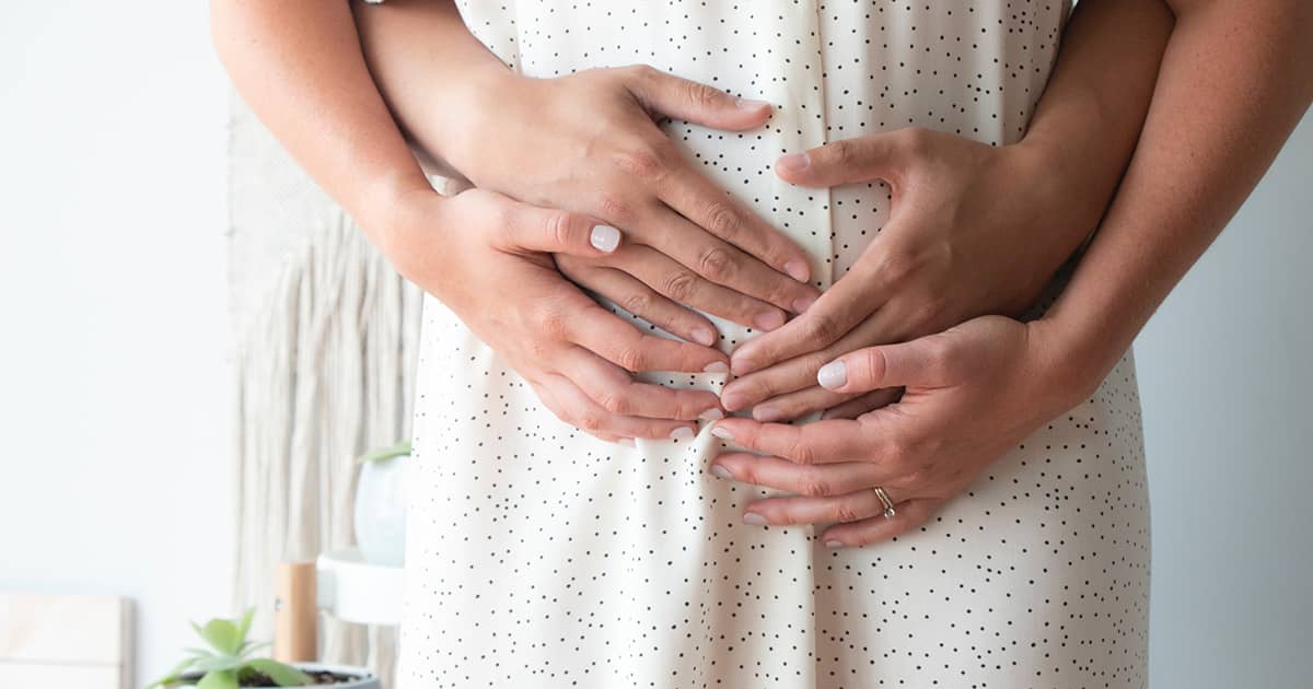 a pregnant woman with her partner holding her belly