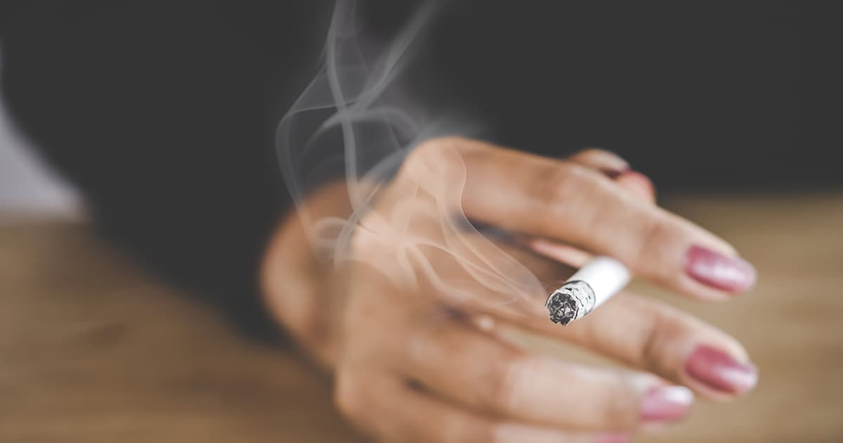 a woman holding a lit cigarette in a hand