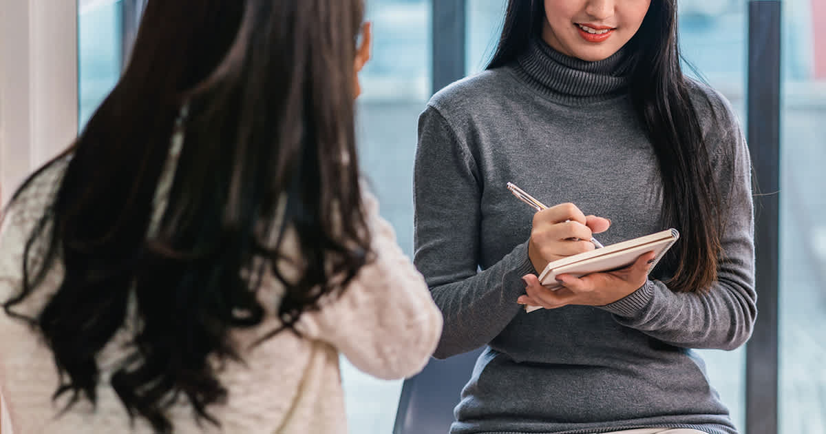 two women talking while one of them writes notes