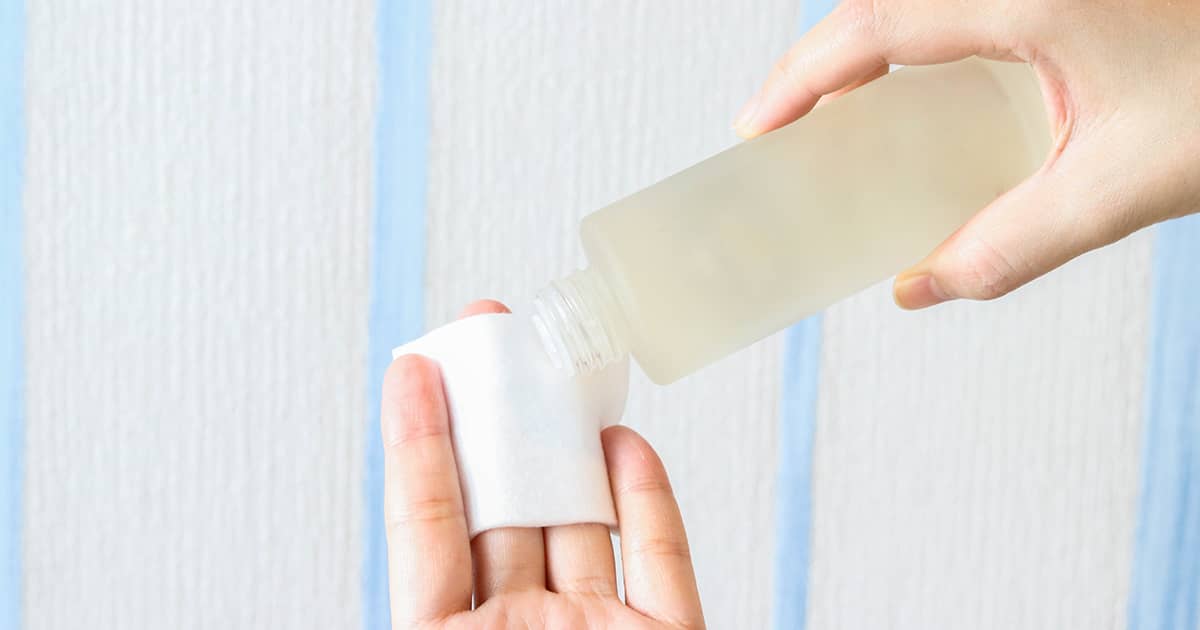 a woman pouring toner on a cotton pad