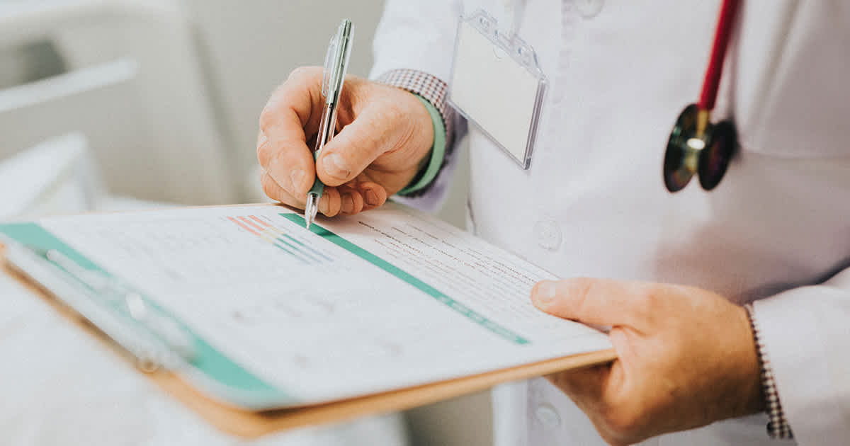 doctor writing on paper on a clipboard