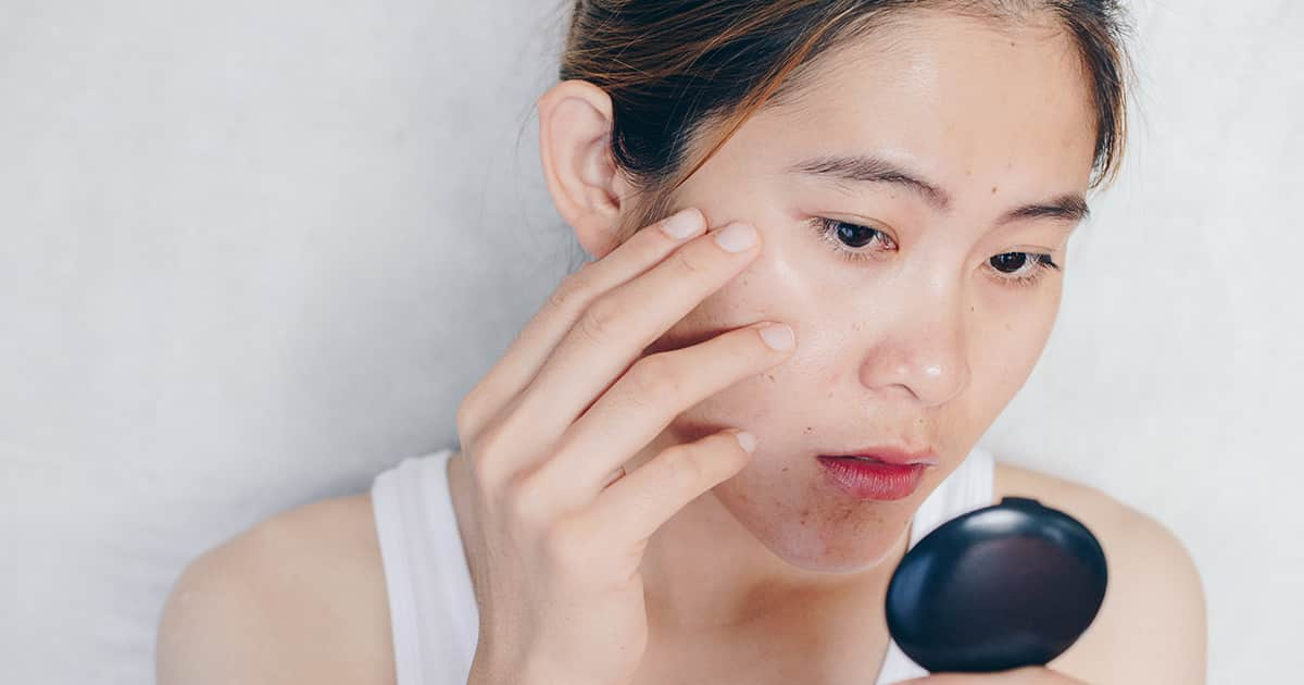 a woman looking at her face in a mirror