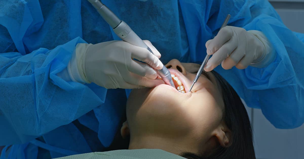 a female patient getting her teeth cleaned by a dentist