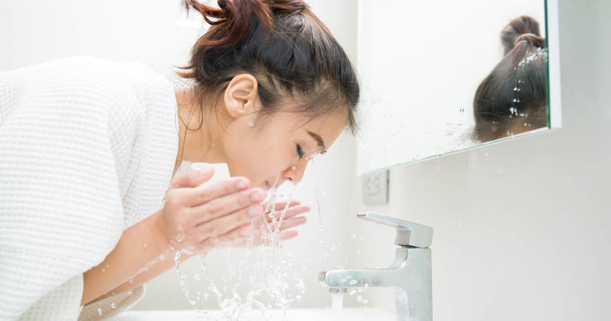 a woman washing her face in her bathroom