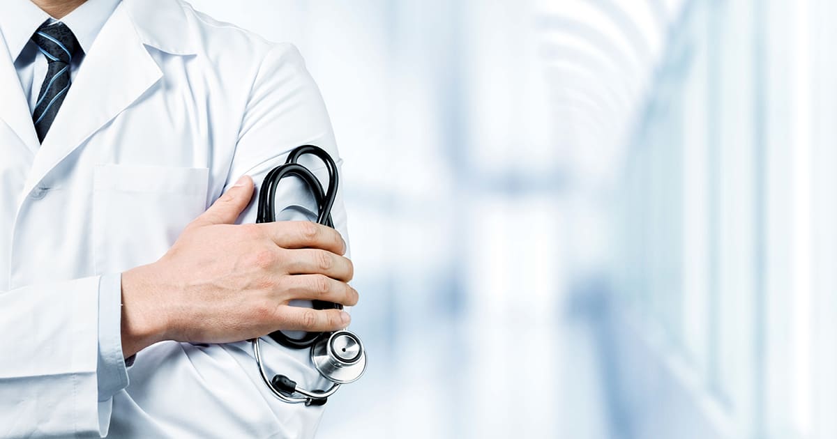 doctor holding stethoscope in hospital corridor