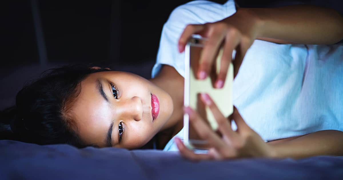 asian kid using phone on bed