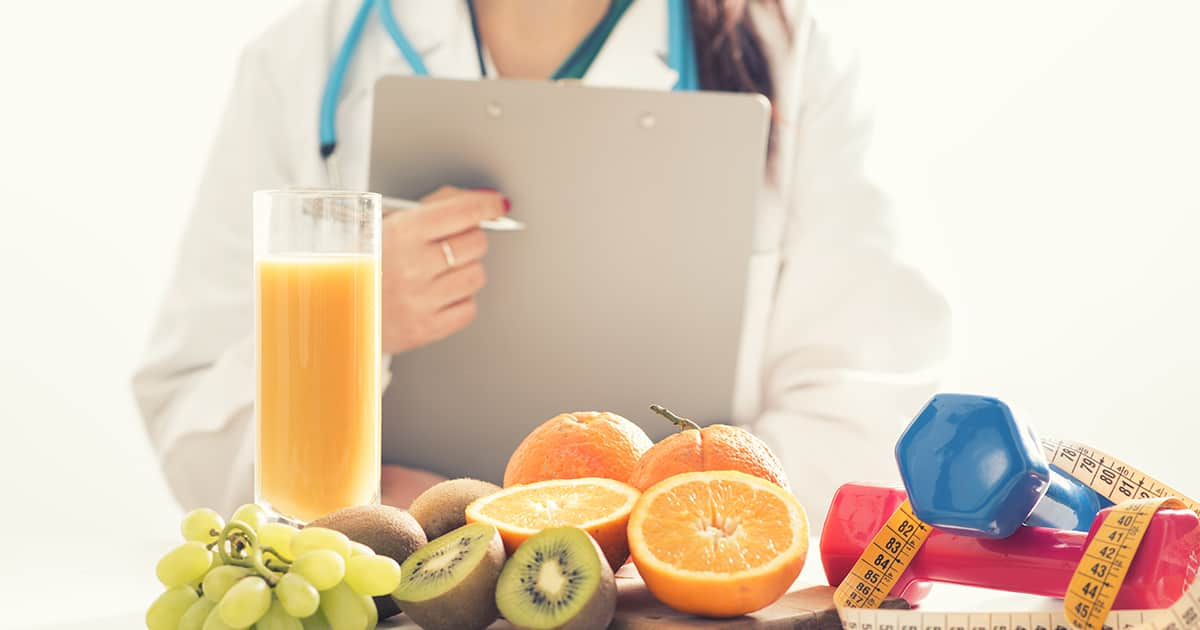 nutritionist with fruits and wellness equipment on table